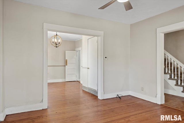 spare room featuring hardwood / wood-style floors and ceiling fan with notable chandelier