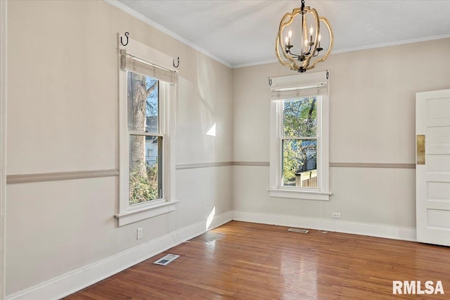 empty room featuring a chandelier, crown molding, and wood-type flooring