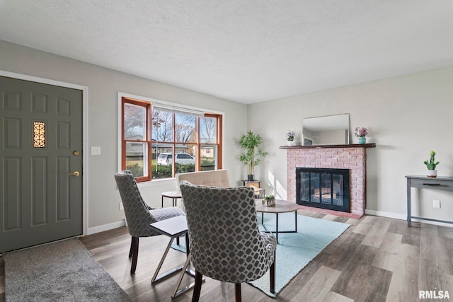 living room with hardwood / wood-style flooring, a textured ceiling, and a brick fireplace