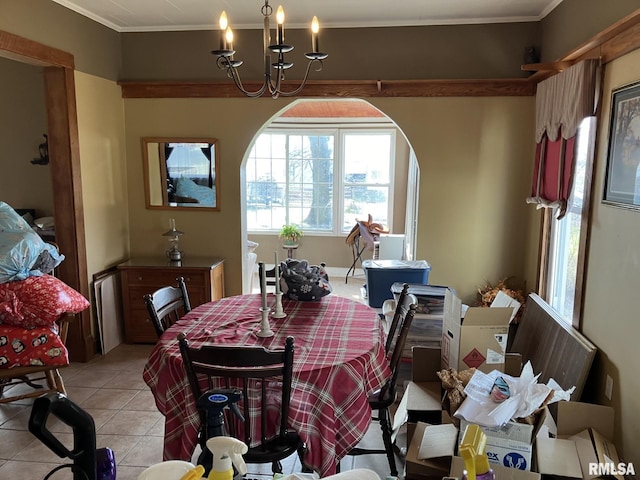 dining space with light tile patterned floors, ornamental molding, and a notable chandelier