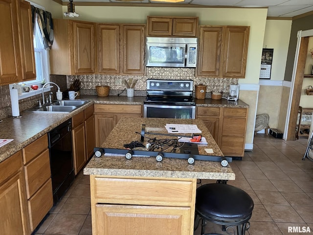 kitchen with a kitchen breakfast bar, sink, a kitchen island, and appliances with stainless steel finishes