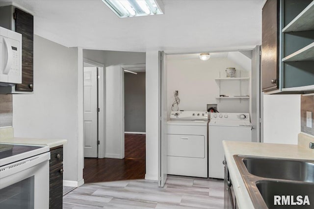 kitchen featuring white appliances, light hardwood / wood-style floors, washer and clothes dryer, and sink