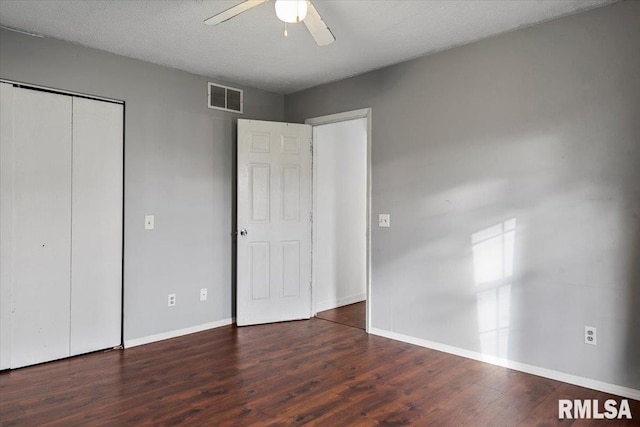 unfurnished bedroom with a textured ceiling, dark hardwood / wood-style flooring, a closet, and ceiling fan