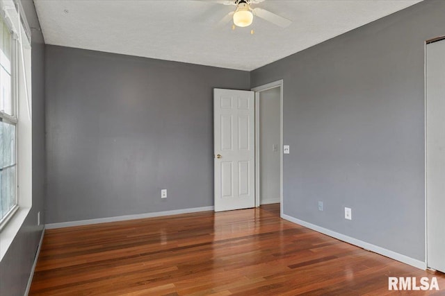 empty room featuring ceiling fan, plenty of natural light, wood-type flooring, and a textured ceiling