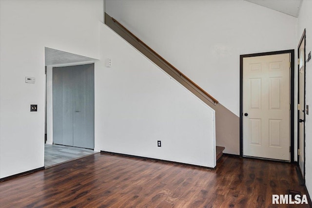 empty room with high vaulted ceiling and dark wood-type flooring