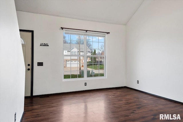 empty room with dark hardwood / wood-style flooring and lofted ceiling