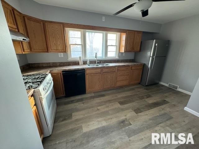 kitchen featuring dishwasher, sink, stainless steel fridge, hardwood / wood-style flooring, and white gas range oven