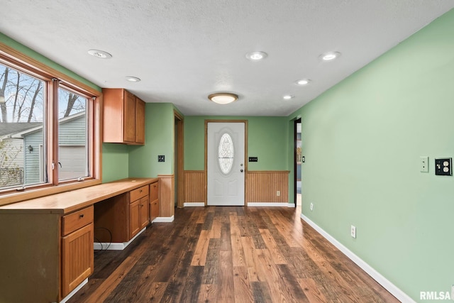 kitchen with a textured ceiling, built in desk, dark hardwood / wood-style floors, and butcher block counters