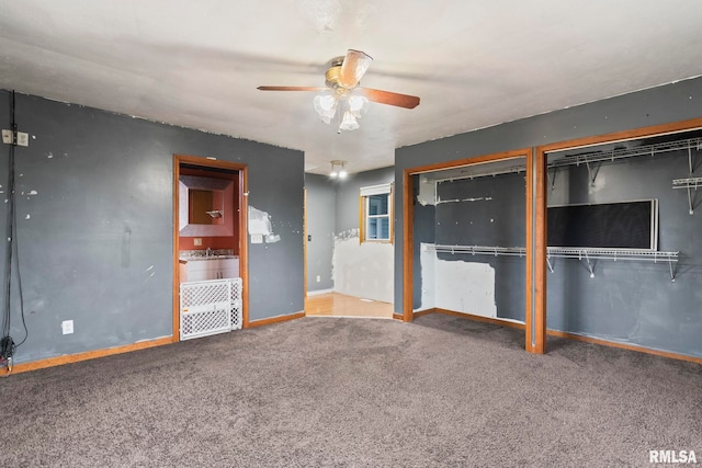 unfurnished bedroom with ceiling fan, carpet, and two closets