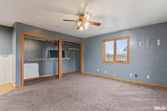 unfurnished bedroom featuring carpet, two closets, and ceiling fan