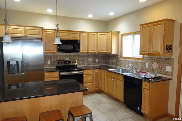 kitchen featuring sink, dark stone countertops, pendant lighting, a kitchen bar, and black appliances