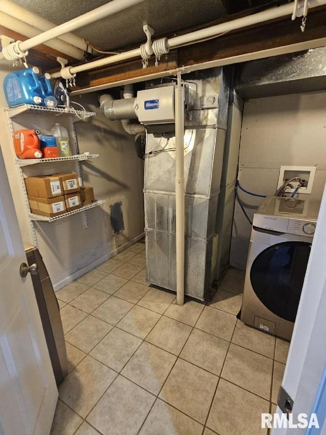 clothes washing area featuring washer / clothes dryer, heating unit, and light tile patterned flooring