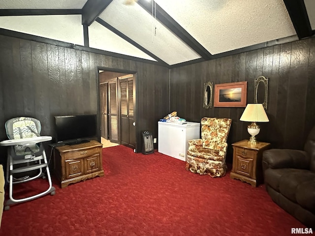 living room featuring a textured ceiling, wood walls, carpet flooring, and vaulted ceiling with beams