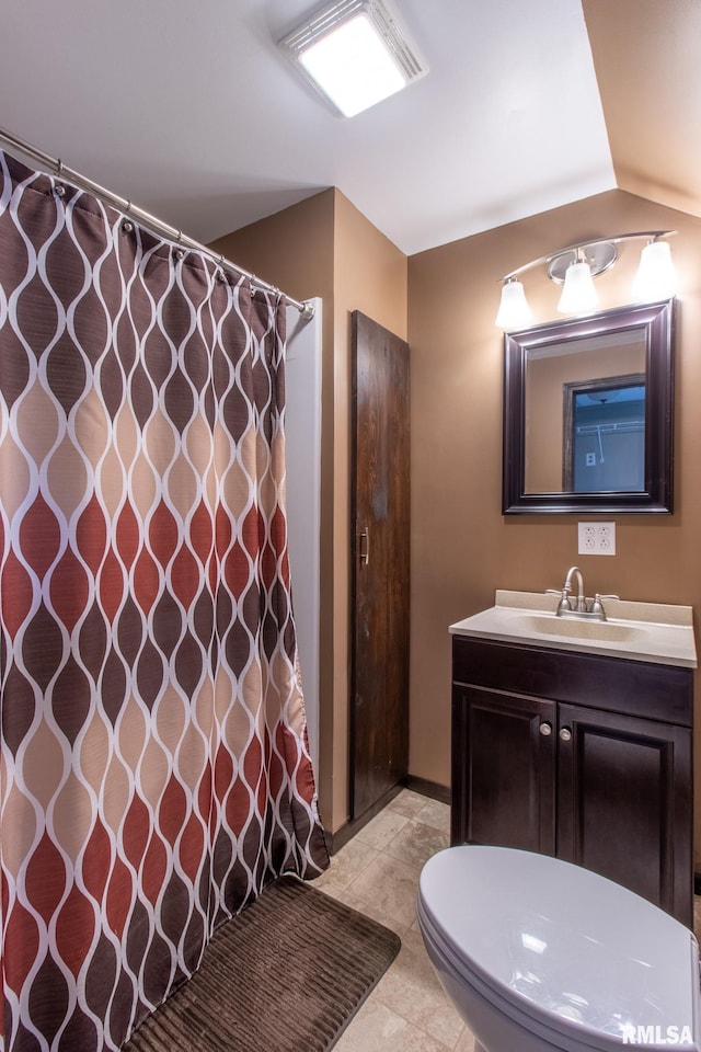 bathroom with toilet, vanity, vaulted ceiling, and tile patterned flooring