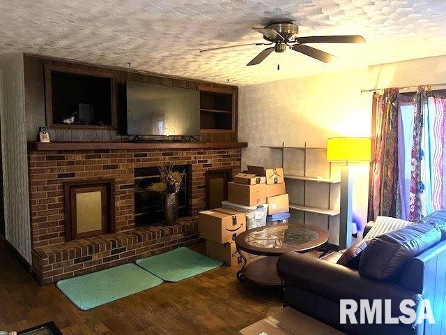 living room featuring a textured ceiling, hardwood / wood-style flooring, and ceiling fan