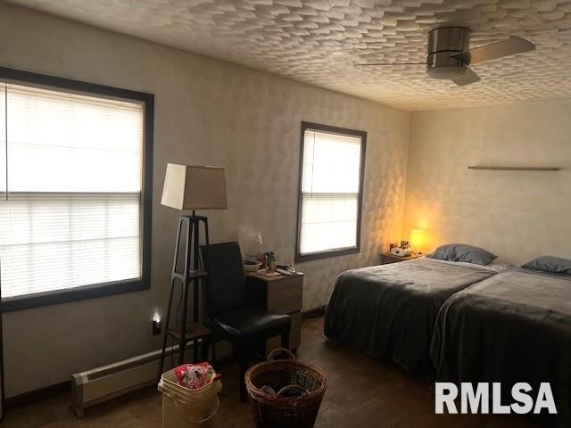 bedroom featuring a textured ceiling and a baseboard heating unit