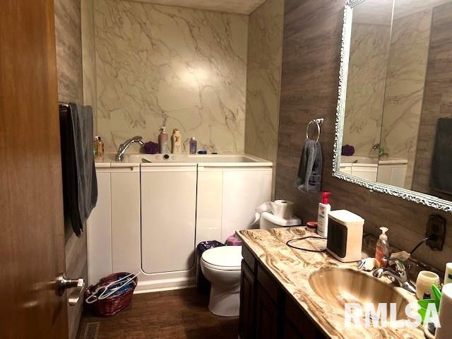 bathroom with wood-type flooring, vanity, and toilet