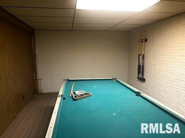 rec room with pool table, a drop ceiling, and brick wall