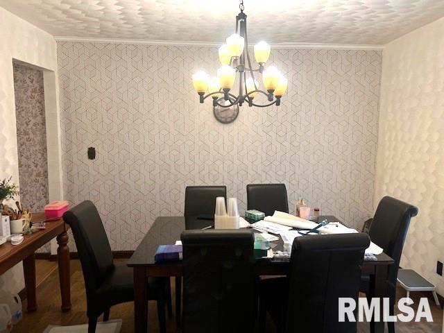 dining area with hardwood / wood-style floors, ornamental molding, a textured ceiling, and an inviting chandelier