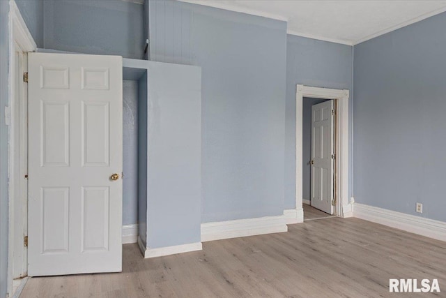 spare room with crown molding and light wood-type flooring