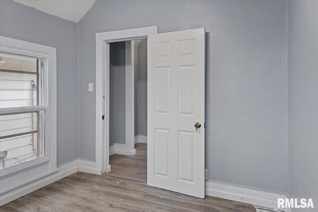 unfurnished bedroom featuring light hardwood / wood-style flooring and vaulted ceiling