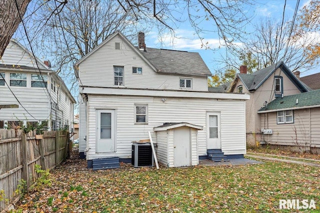 rear view of property featuring central air condition unit and a yard