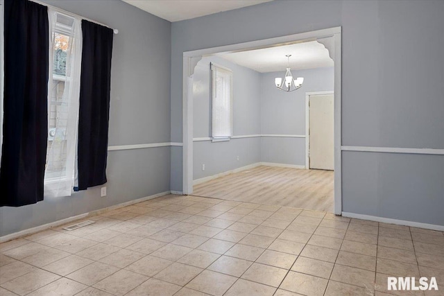 empty room with light hardwood / wood-style floors and an inviting chandelier