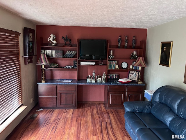 office space featuring dark hardwood / wood-style flooring, a textured ceiling, and built in desk