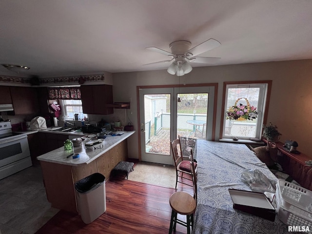 kitchen with electric range, ceiling fan, hardwood / wood-style flooring, kitchen peninsula, and extractor fan