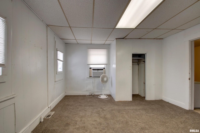 unfurnished bedroom with carpet flooring, a drop ceiling, and cooling unit