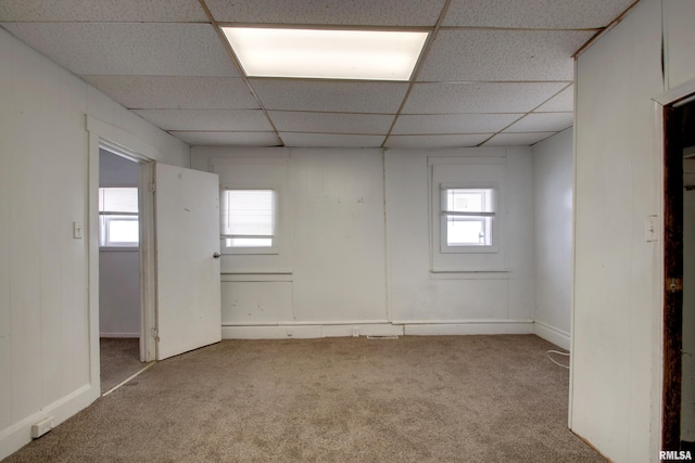 empty room featuring a drop ceiling and light colored carpet