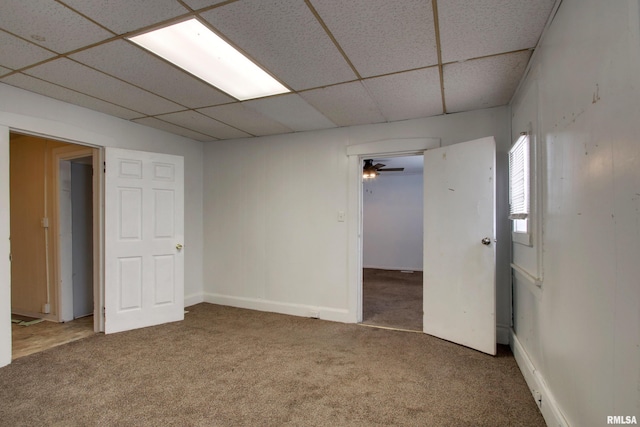 empty room featuring carpet flooring, a paneled ceiling, and ceiling fan