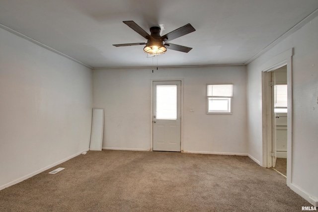 carpeted spare room with ceiling fan and ornamental molding