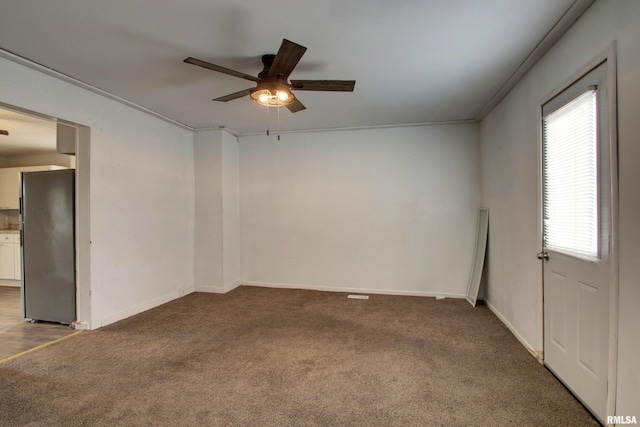 spare room with ceiling fan, crown molding, and carpet