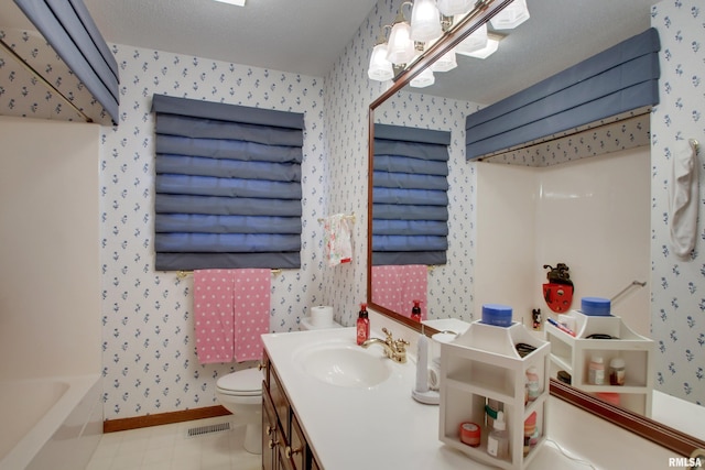 bathroom with vanity, toilet, and a textured ceiling