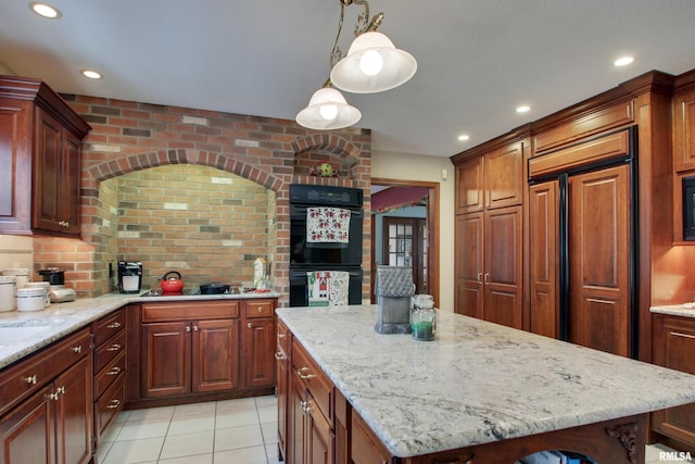 kitchen with light stone counters, black appliances, light tile patterned floors, decorative light fixtures, and a center island