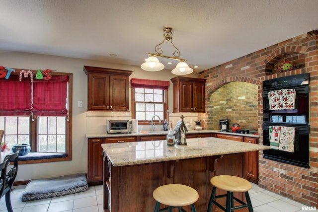 kitchen featuring light tile patterned flooring, a kitchen breakfast bar, sink, double oven, and a kitchen island