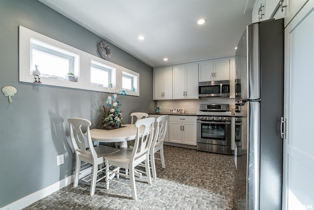 kitchen featuring decorative backsplash, white cabinetry, and stainless steel appliances