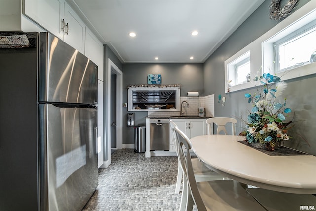 kitchen with appliances with stainless steel finishes, tasteful backsplash, white cabinetry, and sink