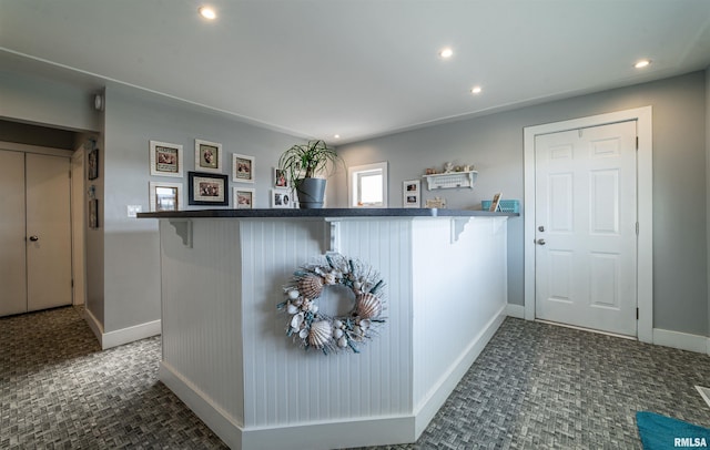 kitchen with a kitchen bar, dark colored carpet, and kitchen peninsula