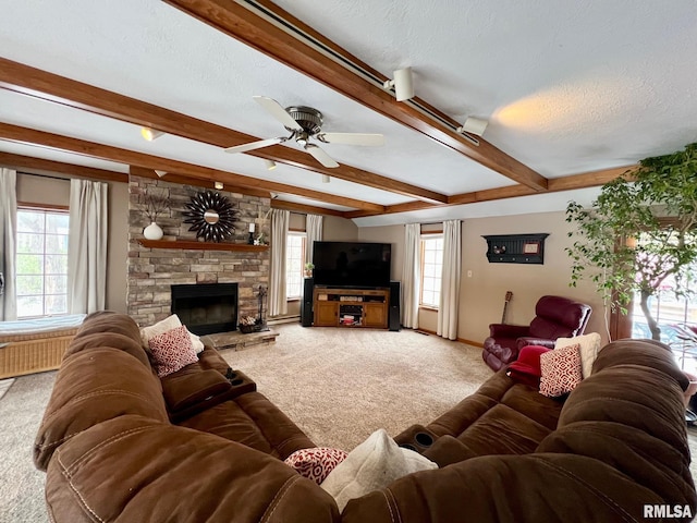 carpeted living room featuring beamed ceiling, a textured ceiling, a stone fireplace, and ceiling fan