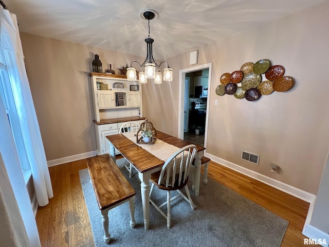 dining room with hardwood / wood-style floors and a chandelier