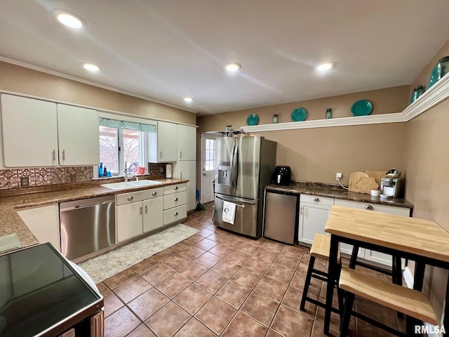 kitchen with white cabinetry, sink, stainless steel appliances, tile patterned floors, and decorative backsplash