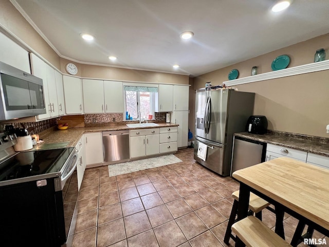 kitchen with white cabinetry, sink, tasteful backsplash, appliances with stainless steel finishes, and ornamental molding