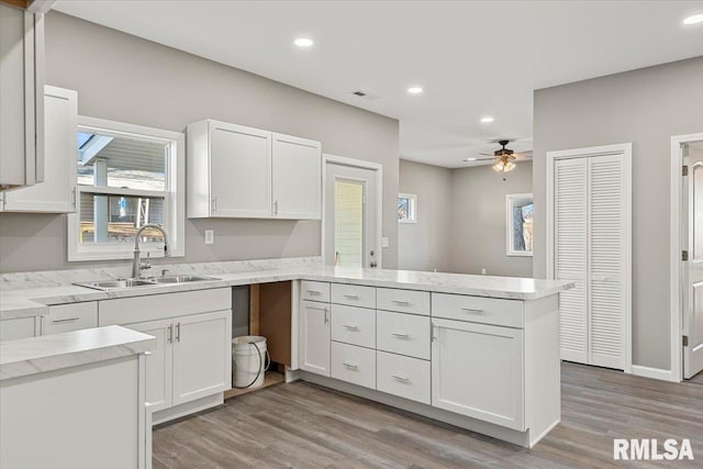 kitchen featuring ceiling fan, sink, kitchen peninsula, light hardwood / wood-style floors, and white cabinets