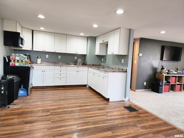 kitchen with dark hardwood / wood-style floors, dark stone countertops, white cabinetry, and sink