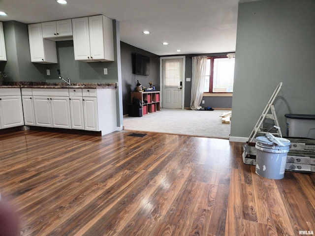 kitchen with dark carpet and white cabinetry