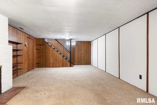 basement featuring carpet flooring, wooden walls, a fireplace, and a textured ceiling