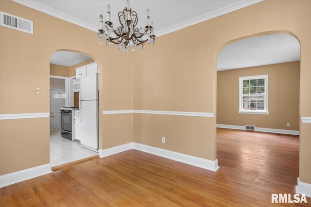 unfurnished room with light hardwood / wood-style floors, crown molding, and an inviting chandelier