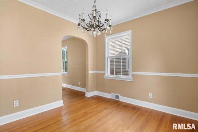 spare room featuring wood-type flooring, an inviting chandelier, and ornamental molding